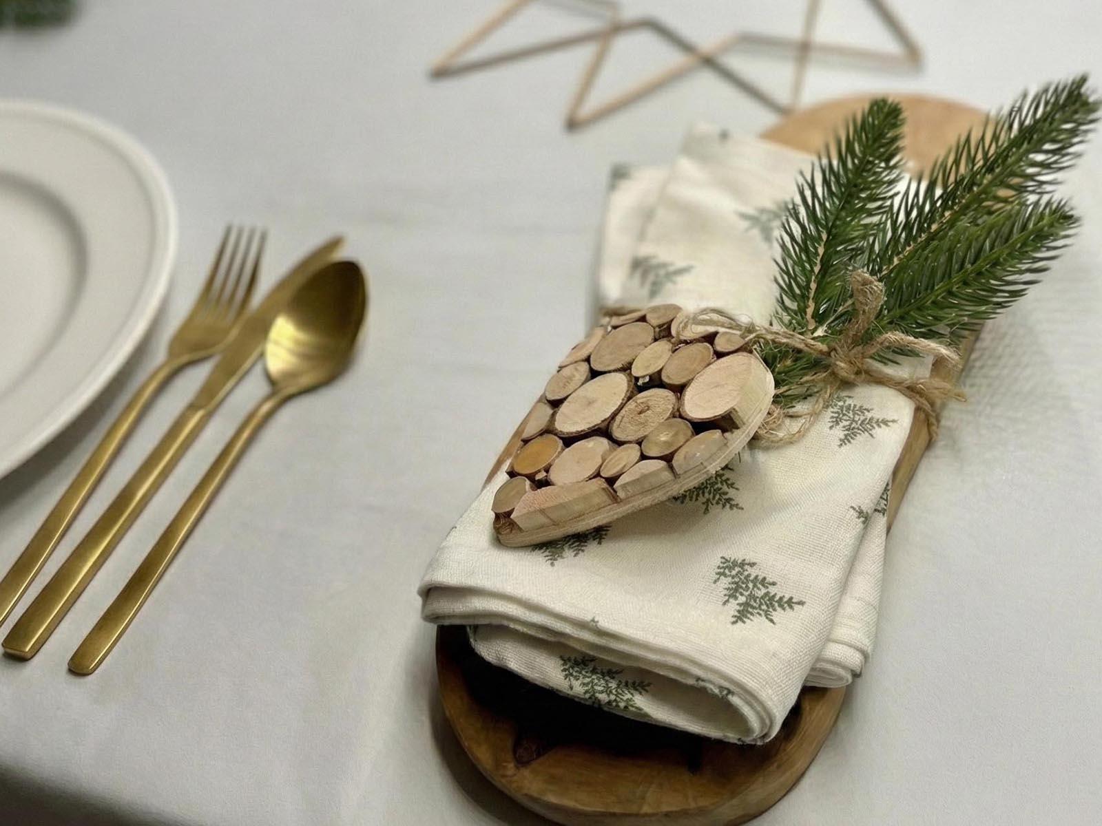 Gałązka sztucznej choinki FairyTrees przywiązana do zwiniętej serwetki z drewnianym sercem i sznurkiem to świetny sposób na wykorzystanie starej choinki.