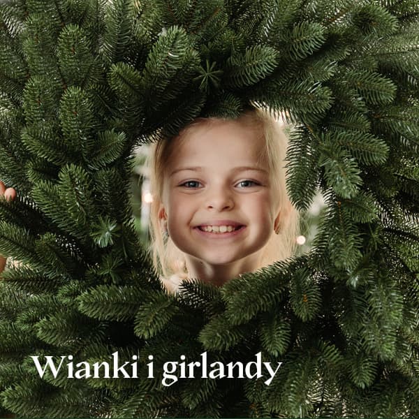 Dziewczynka zagląda przez wianek bożonarodzeniowy marki FairyTrees